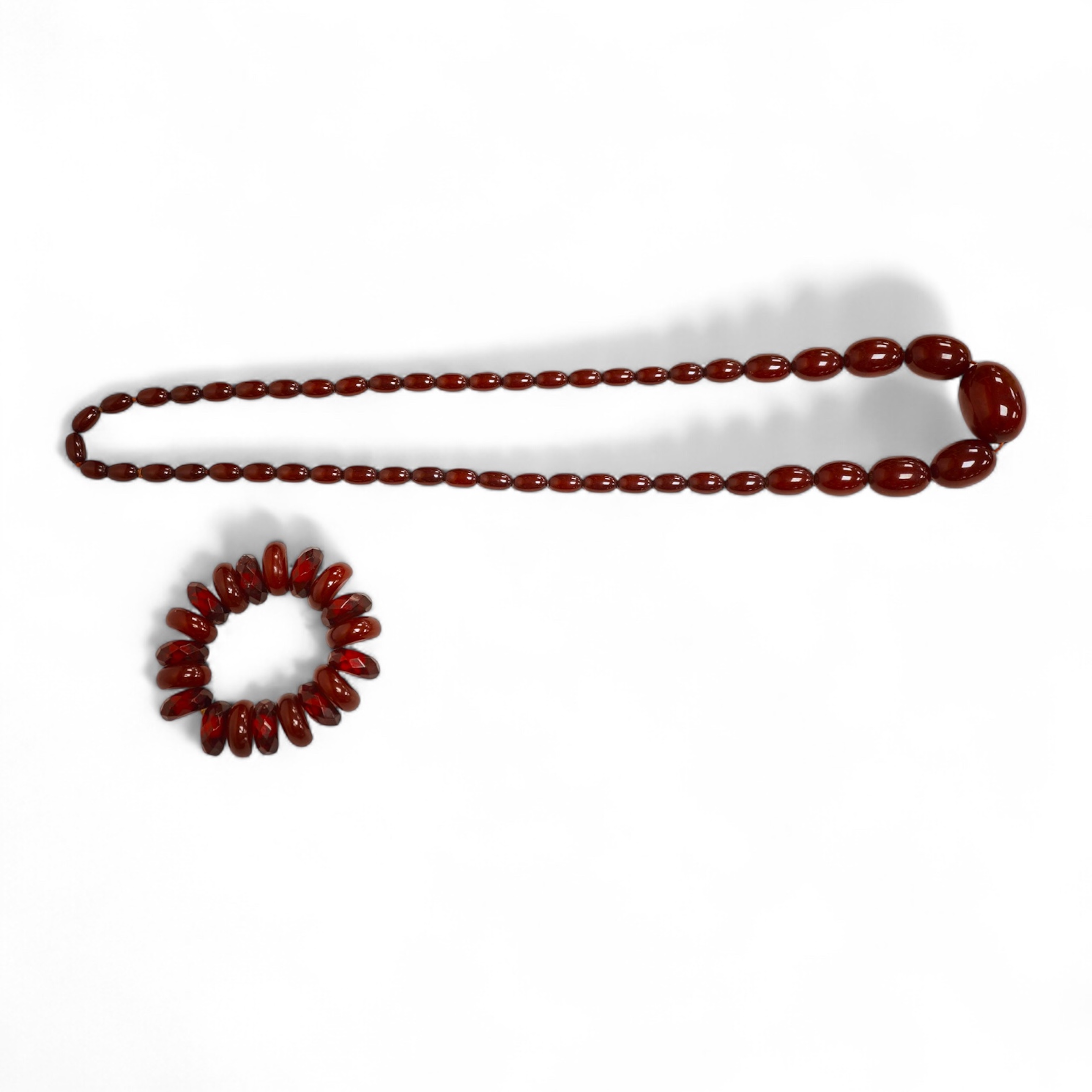 A single strand graduated oval simulated amber bead necklace, 72cm, gross weight 64 grams, together with a simulated cherry amber bracelet.
